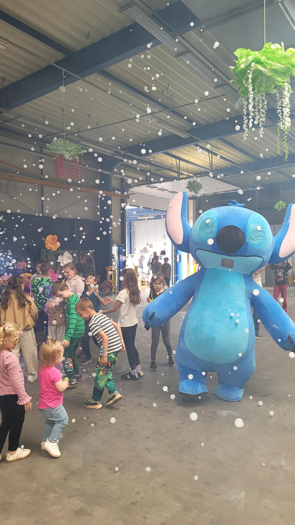 Dzieci łapiące bańki mydlane obok maskotki gigant podczas pokazu bubble show