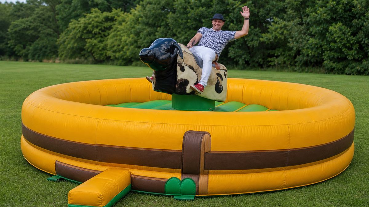 Byk Rodeo — mechaniczny byk na żółtej dmuchanej arenie na trawie
