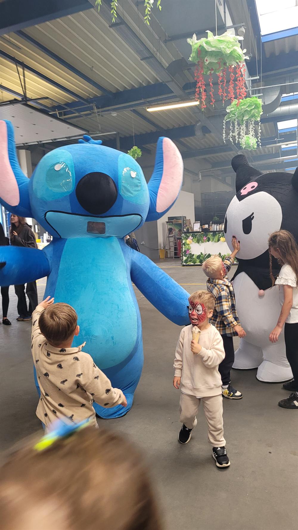Chłopiec z twarzą pomalowaną w motyw Spider-Mana obok maskotek gigant