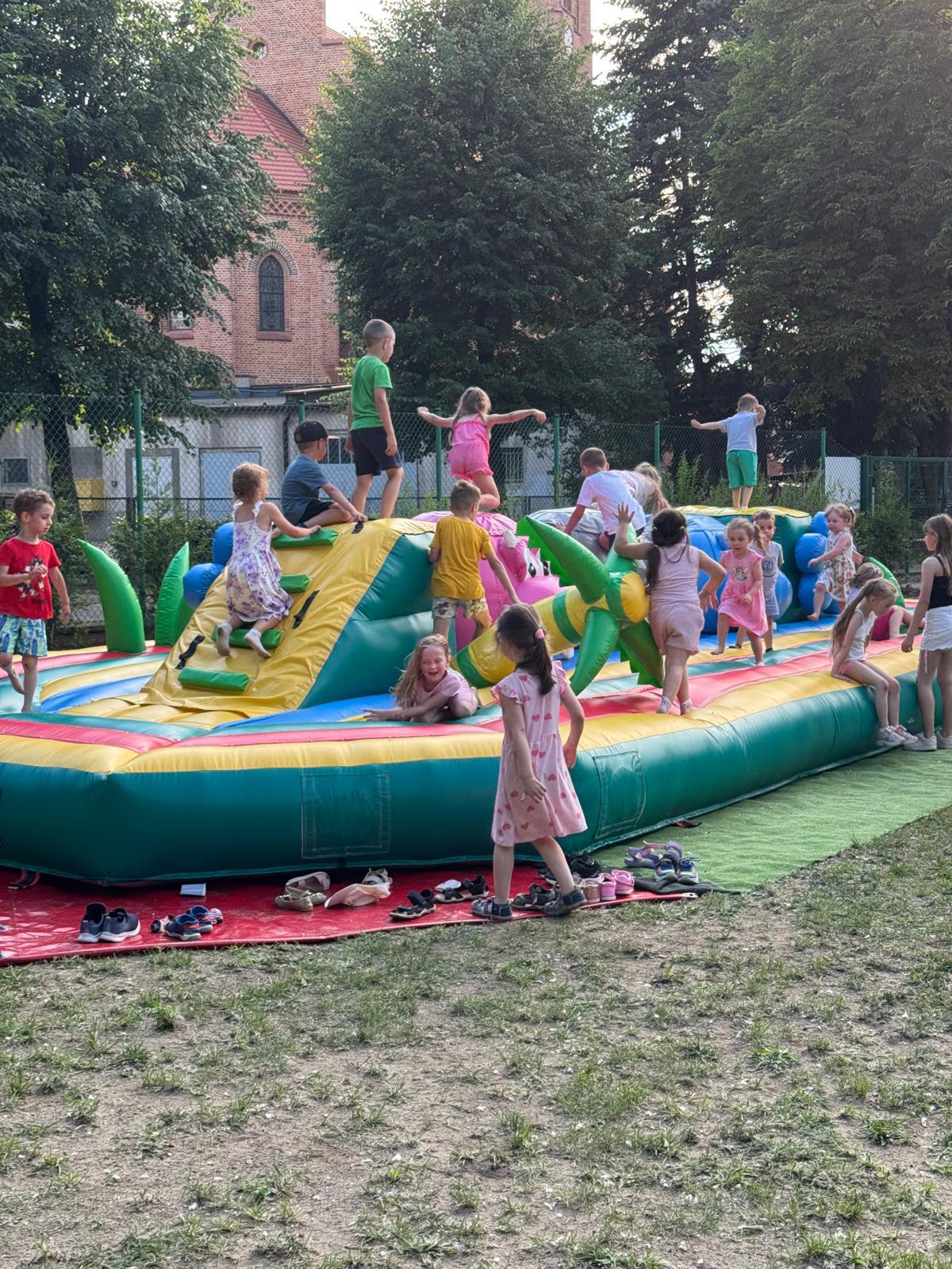 Kukle Hipcio — długi niski dmuchaniec z figurami, dzieci bawiące się na nim