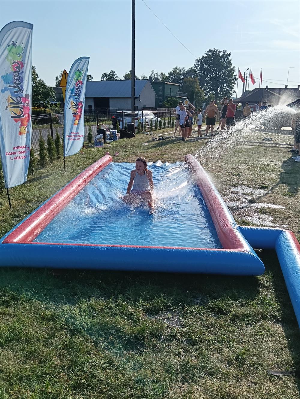 Dzieci zjeżdżające po długim dmuchanym ślizgu wodnym